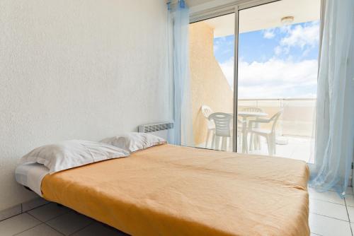 - une chambre avec un lit et un balcon avec une table dans l'établissement Lagrange Vacances Les Résidences, à Sainte-Marie-Plage