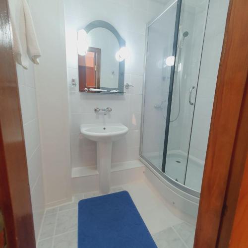 a white bathroom with a sink and a shower at Aktobe Hotel in Aktobe