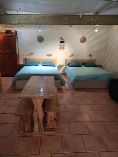 a bedroom with two beds and a wooden table at Chambre atypique : La Grotte in Bez-et-Esparon
