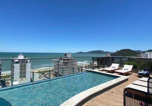 a swimming pool on top of a building with the ocean at Brava Mundo Hotel Boutique OFICIAL in Itajaí