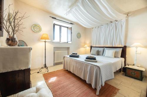 1 dormitorio con 1 cama grande con dosel blanco en Trullo Gioia, en Vaglio di Basilicata