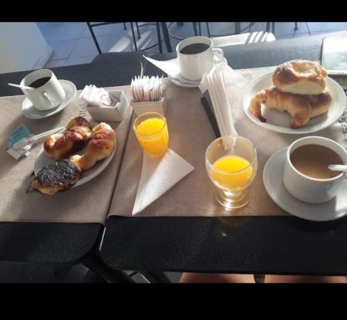 a table with plates of breakfast foods and cups of orange juice at hotel el retorno in Catriel