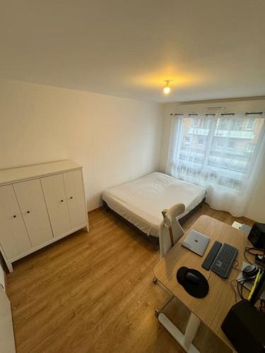 een kleine kamer met een bed en een bureau met een computer bij Appartement JO, proche Paris in Guyancourt