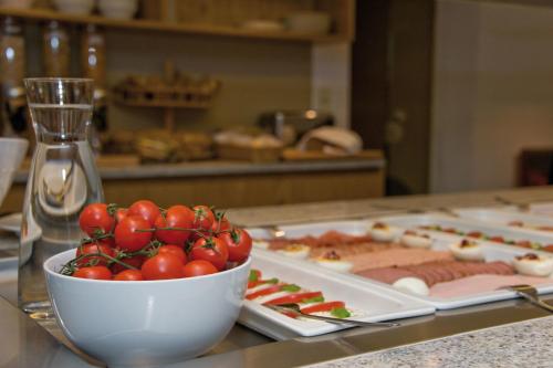 a table with a bowl of tomatoes and meats at Hotel Garni Rauch in Sankt Anton am Arlberg