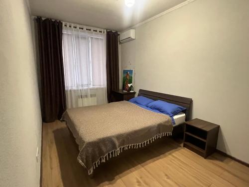 ein Schlafzimmer mit einem Bett mit blauen Kissen und einem Fenster in der Unterkunft Spacious duplex flat 127 sq m in Bischkek