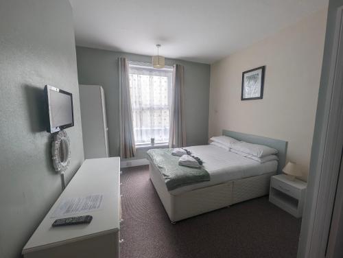 a small bedroom with a bed and a desk at Royal Pier in Sandown