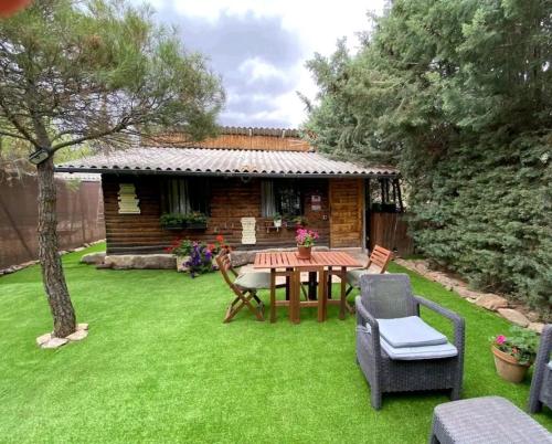 einen Garten mit Tisch und Stühlen und ein Haus in der Unterkunft Cabaña ecologica del lago in Paredes de Buitrago
