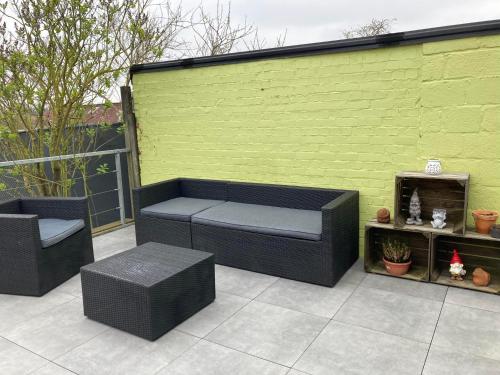 a patio with two seats and a green wall at Het Zonnetje Zonnebeke in Zonnebeke