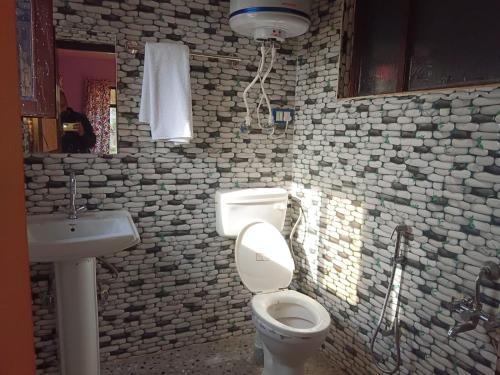 La salle de bains est pourvue de toilettes blanches et d'un lavabo. dans l'établissement Apple Garden View and Restaurant, à Pahalgām