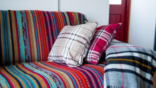 a couch with two pillows and a blanket on it at Old School Byre in Stoer