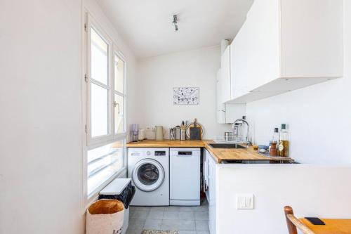 une cuisine blanche avec une machine à laver et une fenêtre dans l'établissement GuestReady - City center gem near attractions, à Paris