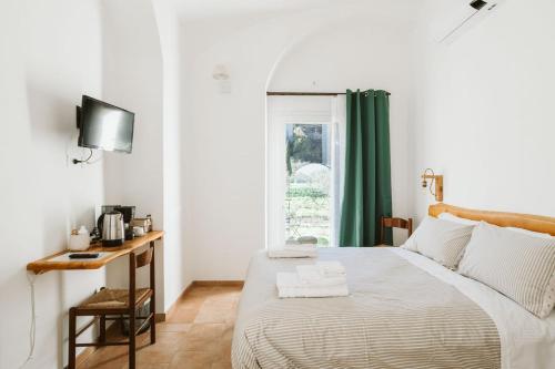 a bedroom with a bed with a desk and a window at Agriturismo Il Canto delle rane in Finale Ligure