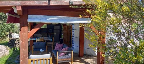 una pequeña casa con toldo y sillas en un porche en Yourte au calme avec piscine, en Carbuccia