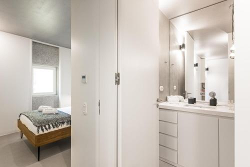 uma casa de banho branca com um lavatório e um espelho em GuestReady - Cardosas Fourth no Porto