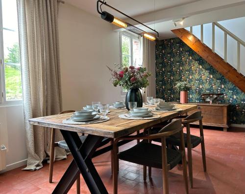 une table à manger avec des chaises et un vase de fleurs dans l'établissement La Maison Beaumont - Normandie, à Beaumont-en-Auge