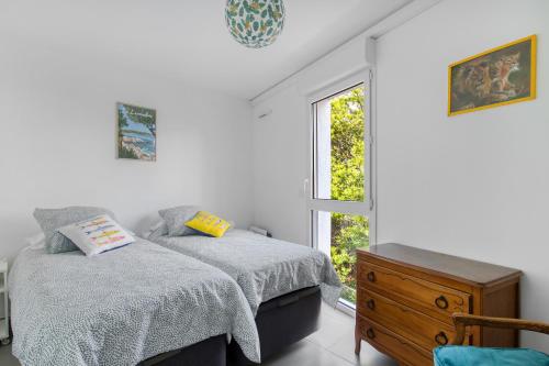 a bedroom with two beds and a window at Nouvelle Ère - Appt à moins d’un km de la plage in Le Lavandou
