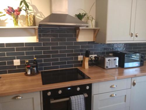a kitchen counter with a sink and a stove at The Eaves, Glastonbury High Street in Glastonbury