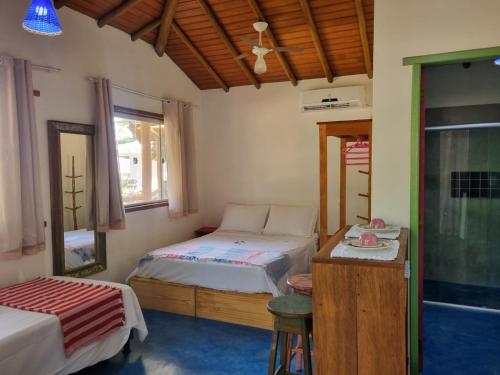 1 dormitorio con 2 camas, mesa y ventana en Pousada Casa de Sapê, en Arraial d'Ajuda