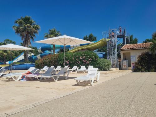 - un groupe de chaises longues et de parasols dans un parc aquatique dans l'établissement MOBILE HOME CLIMATISE Vias 2, à Vias
