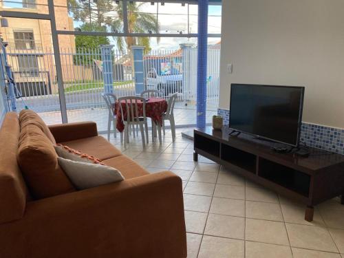 uma sala de estar com um sofá e uma televisão de ecrã plano em Casa do Jardim em Curitiba