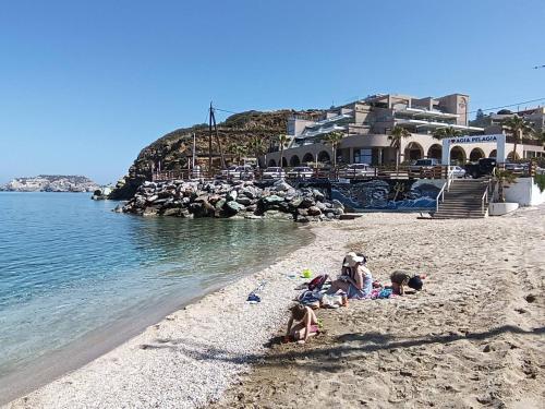 a group of children laying on a beach near the water at Superior Savvas Apartments by the sea in Agia Pelagia