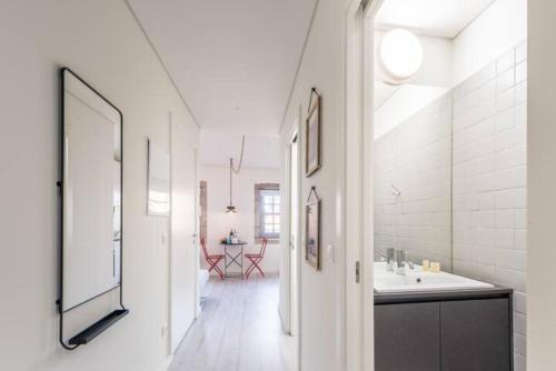 uma casa de banho branca com um lavatório e um espelho em GuestReady - Genuine Oporto Apts - 4 no Porto