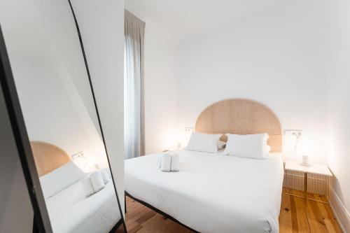 Schlafzimmer mit einem weißen Bett und einem Spiegel in der Unterkunft GuestReady - Casa da Alegria 6 in Porto