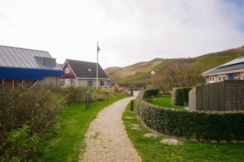 een stenen pad door een dorp met huizen en heuvels bij De Duin Haven - Seinpost 03 - Callantsoog in Callantsoog