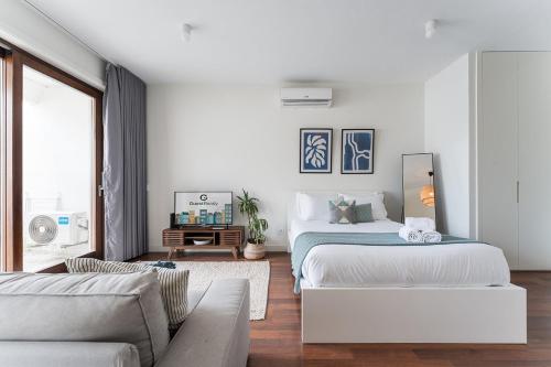 a white bedroom with two beds and a couch at GuestReady - Almada 516 in Porto