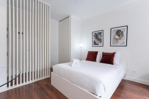 a white bedroom with a large white bed with red pillows at GuestReady - Almada 516 in Porto