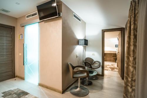 a room with two chairs and a tv on a wall at Hotel Eden Garden Spa in Câmpulung Moldovenesc
