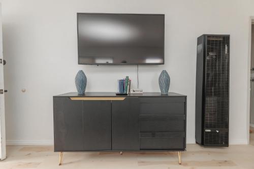 a black dresser with a television on a wall at Cool and Cozy Pad Close to Everything in Los Angeles