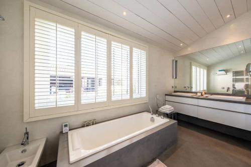 La grande salle de bains est pourvue d'une grande baignoire et d'un lavabo. dans l'établissement Superbe maison d'architecte autour de sa piscine chauffée, à La Flotte