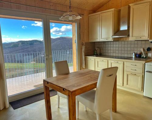 a kitchen with a wooden table and chairs and a balcony at Panoramic apartment on Monte Generoso in Castel San Pietro