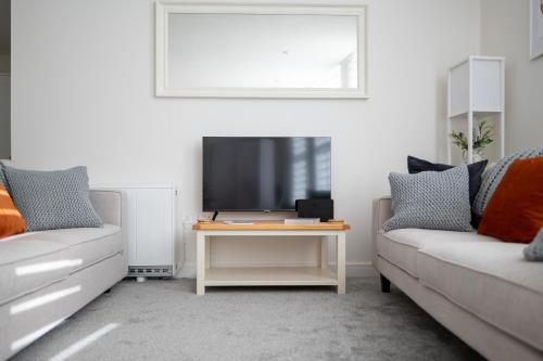 a living room with a couch and a tv at Bright and Spacious 2-Bed Apartment in Sherborne