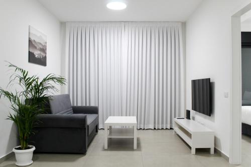 a living room with a couch and a tv at Luxury Suite Apartment #1 By Hashdera Eilat in Eilat