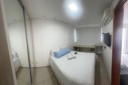 een kleine kamer met een wit bed en een televisie bij Flat espetacular Flamboyant 2 in Goiânia