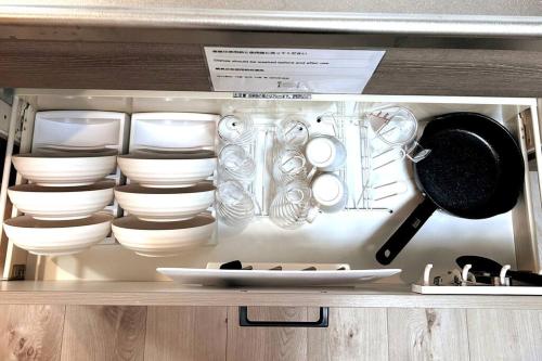a cabinet filled with white dishes and utensils at ゲストルーム上野桜木(上野駅and日暮里駅) in Tokyo