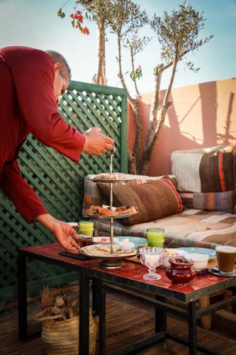 ein Mann serviert Essen auf einem Tisch in der Unterkunft Riad 11 Zitoune in Marrakesch
