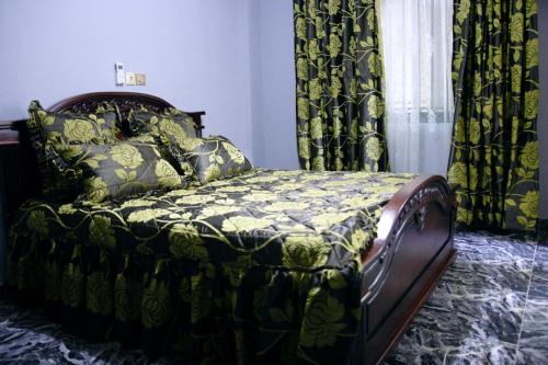 - un lit dans une chambre avec des rideaux dans l'établissement FARLEYVETTE GUEST HOUSE, à Yaoundé
