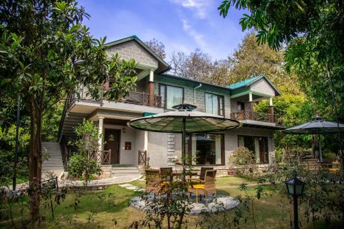 a house with an umbrella in the yard at Aahana Resort - Jim Corbett in Rāmnagar