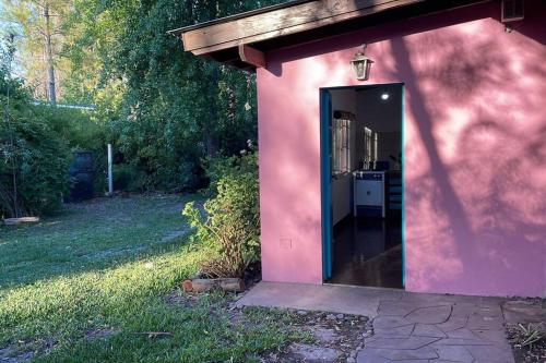 uma casa cor-de-rosa com uma porta num quintal em Casa del bosque em Benavídez