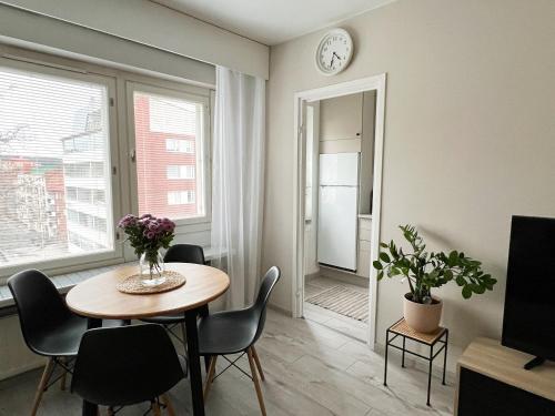 a dining room with a table and chairs and a clock at Bright & Cozy, Renovated Studio in the Lahti Center in Lahti