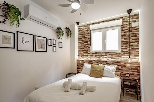 um quarto com uma cama branca e uma parede de tijolos em Apartamentos Santiago Cordero em Madri