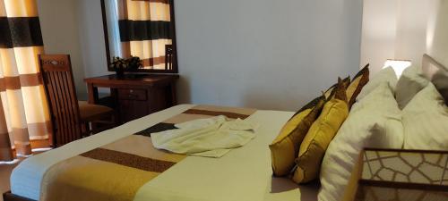 1 dormitorio con 1 cama con almohadas de oro en Empire Valley Hotel, en Kandy