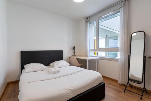 une chambre avec un grand lit et une grande fenêtre dans l'établissement T3 Grenoble, tout confort, balcon, wifi, à Grenoble