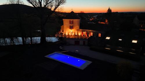 a swimming pool in front of a house at sunset at Le Moulin des Ducs in Épinac-les-Mines