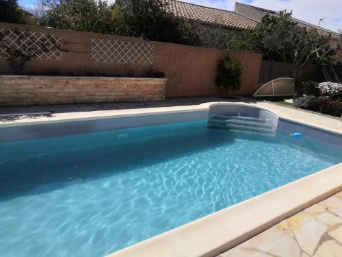 a swimming pool with blue water in a backyard at 2 Chambres avec piscine et spa au calme, mer à proximité. in Portiragnes