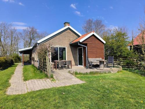 a small house with a table and chairs in a yard at Bungalow - Rust en Ruimte in Ballum