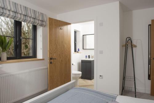 a bedroom with a bathroom with a toilet and a window at Atlantic Point, Porthleven in Porthleven